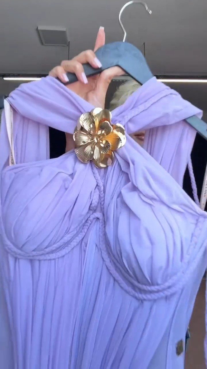 Evening Dress Luxury: 9 Gown Ideas in Satin and Sequins 9 Light purple pleated gown with a gold flower ornament on a hanger