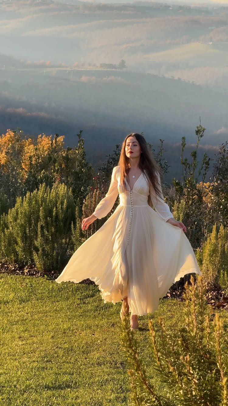 Fairy Tail Dress Ideas: 6 Styles for Fairytale Looks 5 Woman in a flowing white A-line dress standing in a golden grassy field