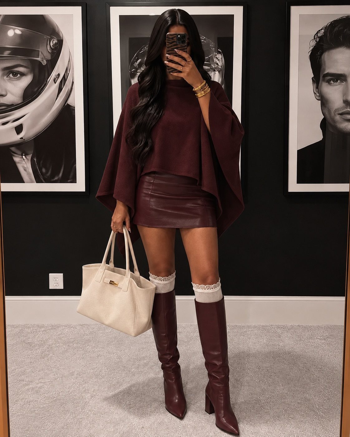 Woman in burgundy sweater, leather mini skirt, and matching boots holding white bag.