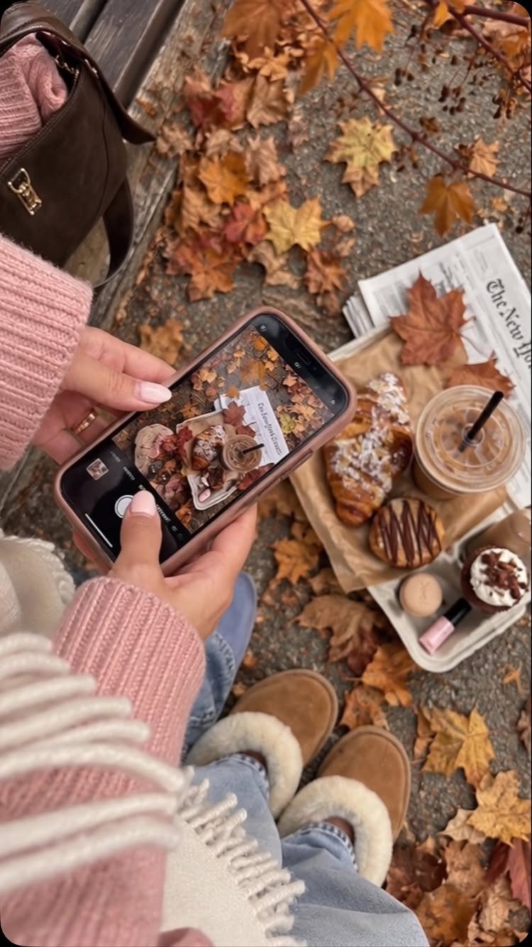Fall Picnic Outfit Ideas: 10 Cozy Looks to Wear 8 Person in pink sweater and jeans photographing autumn treats among fallen leaves