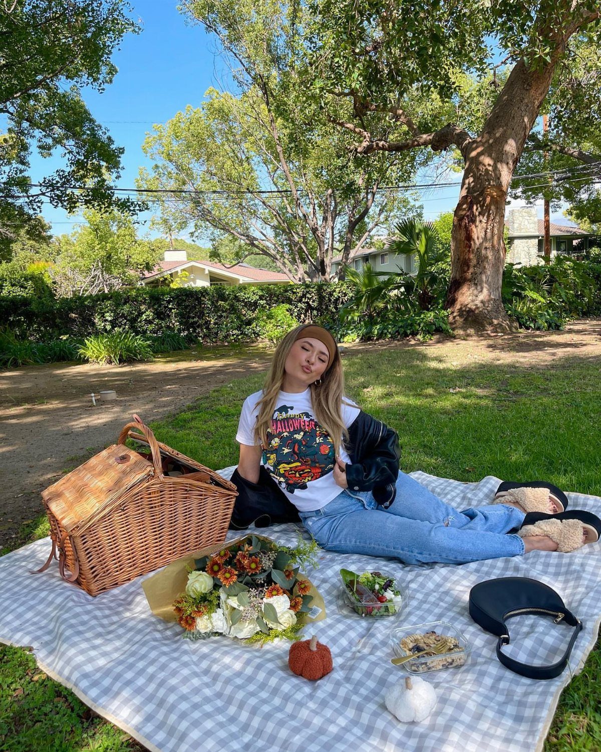 Fall Picnic Outfit Ideas: 10 Cozy Looks to Wear 9 Woman in a leather jacket and jeans sitting on a picnic blanket outdoors.