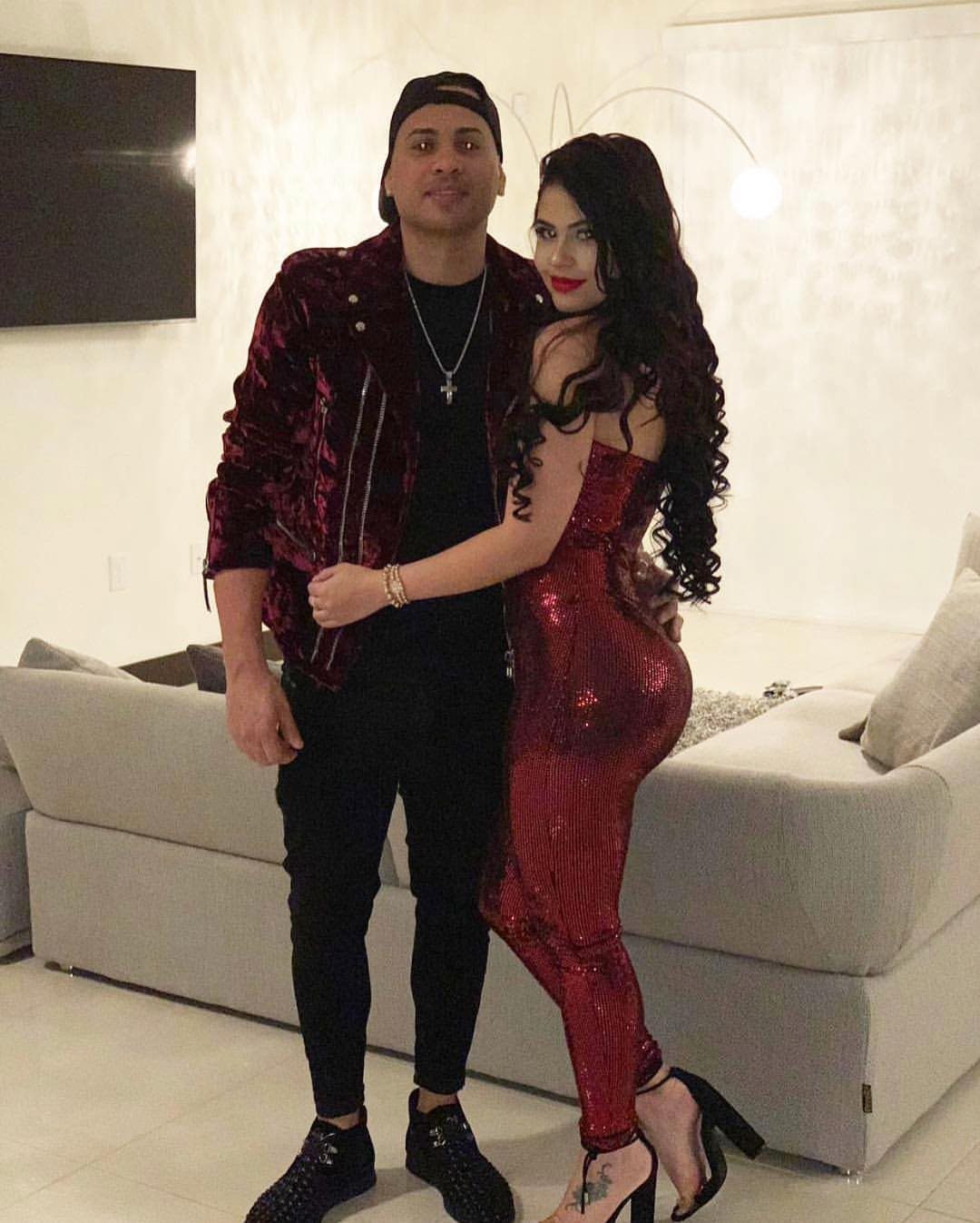 11 Glitz Glam Outfit Ideas with Sequins, Fringe and Fur 6 Woman in a shimmering red metallic jumpsuit posing with a man in velvet.
