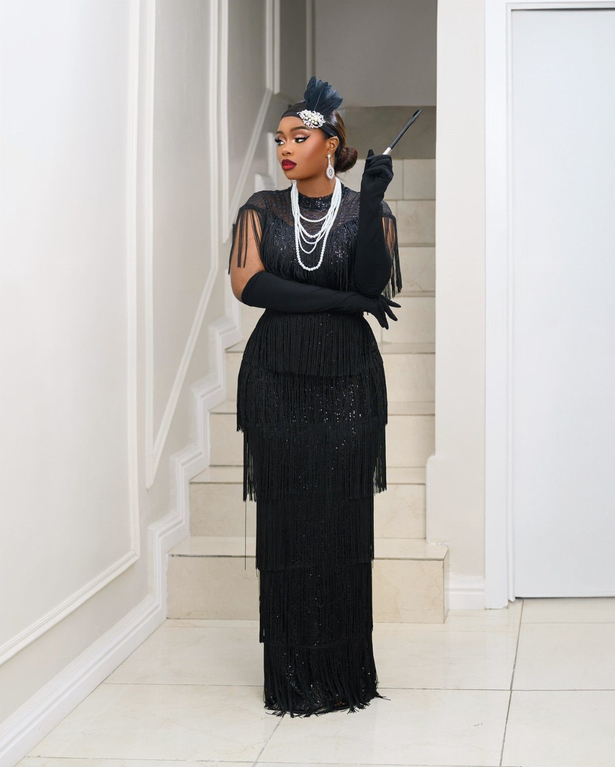 11 Glitz Glam Outfit Ideas with Sequins, Fringe and Fur 11 Woman in a black sequined fringe dress with pearls and feathered headpiece.
