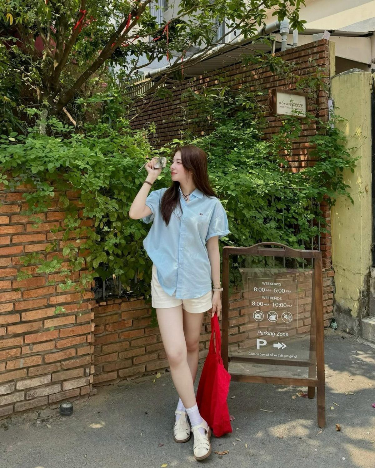 How to Style a Tunic: 9 Ideas From Jeans to Shorts 7 Woman wearing a light blue tunic shirt and white shorts standing by a wall.