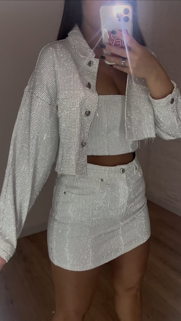 Person wearing a shimmering white cropped jacket and matching mini skirt set.
