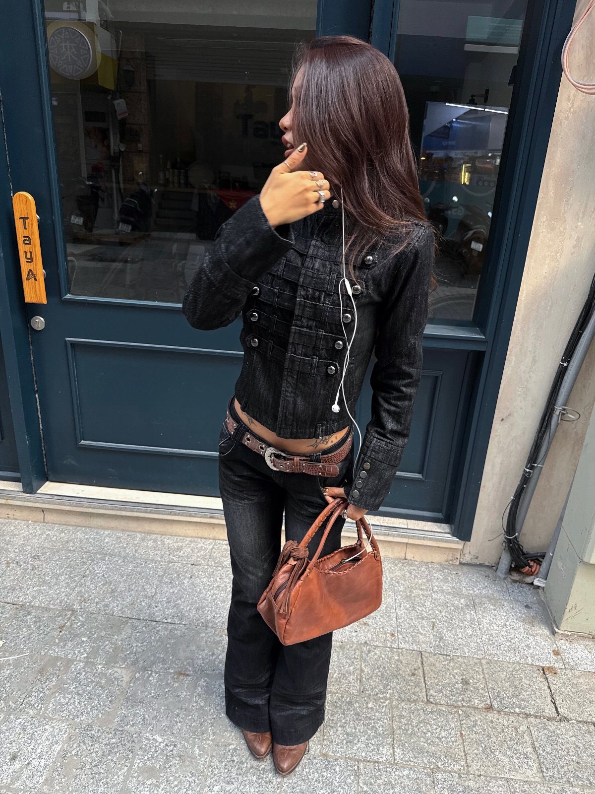 Woman wearing black jeans and brown boots holding a brown leather handbag.