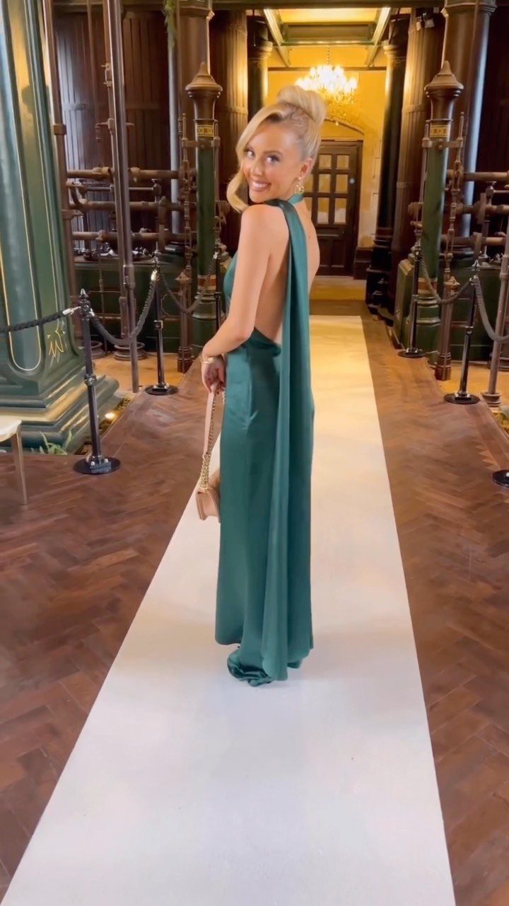 10 Luxury Dress for Wedding Guest Ideas and Styles 4 Woman in emerald green asymmetric maxi dress standing in an ornate hallway