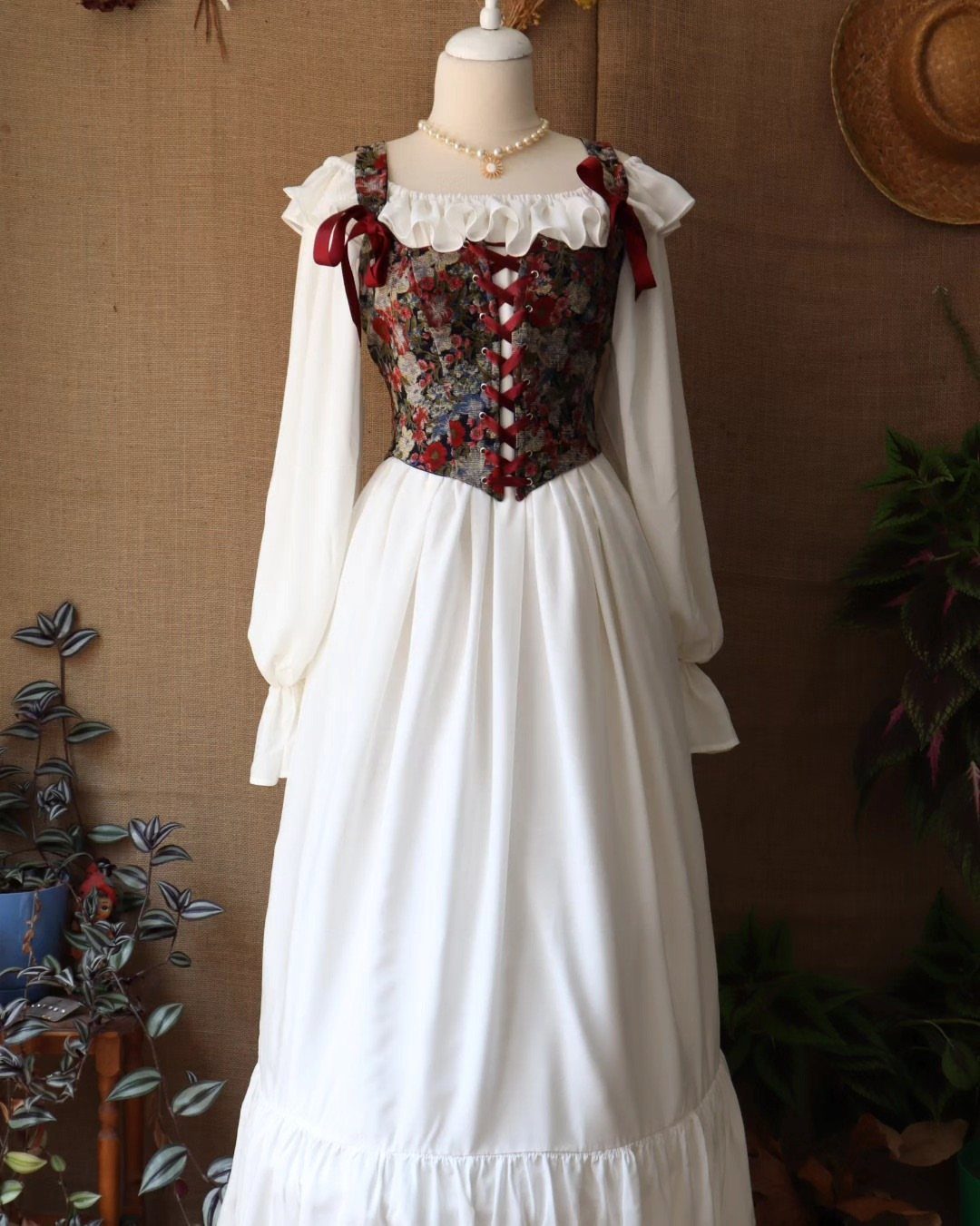Floral red and blue bodice worn over a long white medieval gown on mannequin.