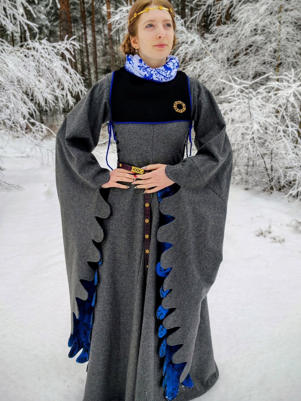 Woman in a grey wool medieval dress and blue scarf in snowy woods