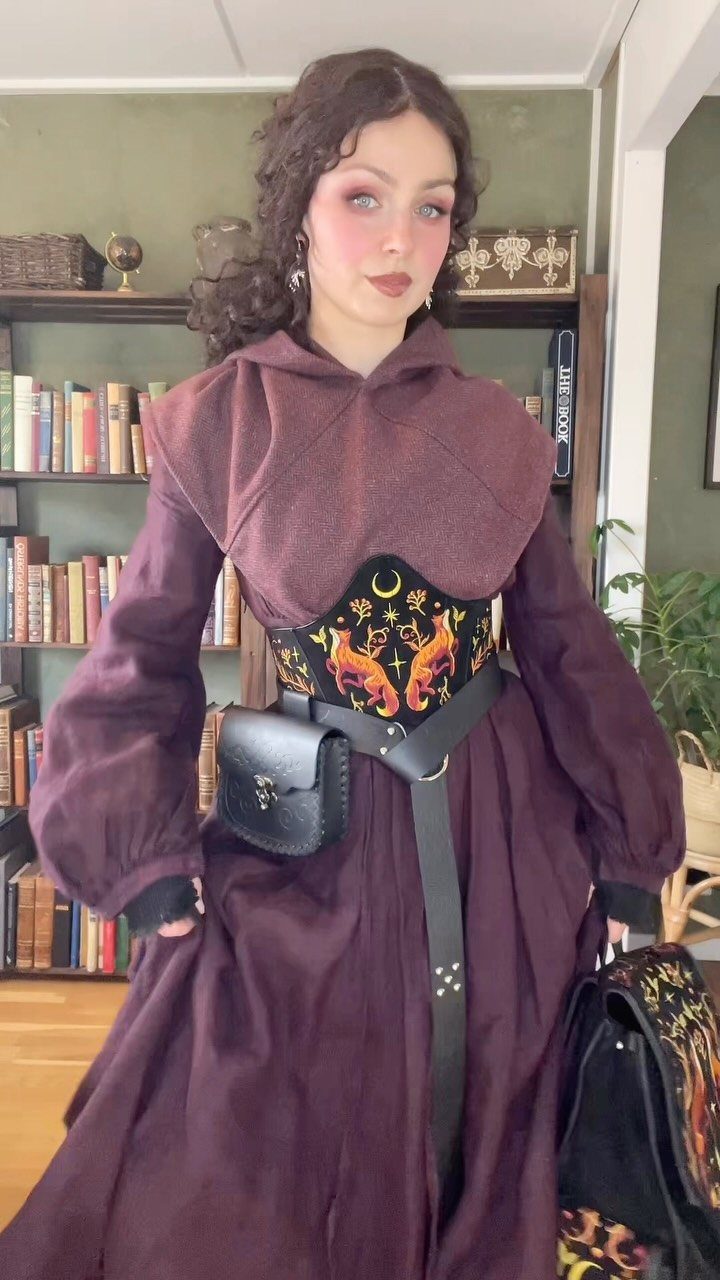 Medieval Period Dress: 12 Women's Styles and Looks 12 Woman in purple medieval dress wearing an embroidered belt and leather pouch.