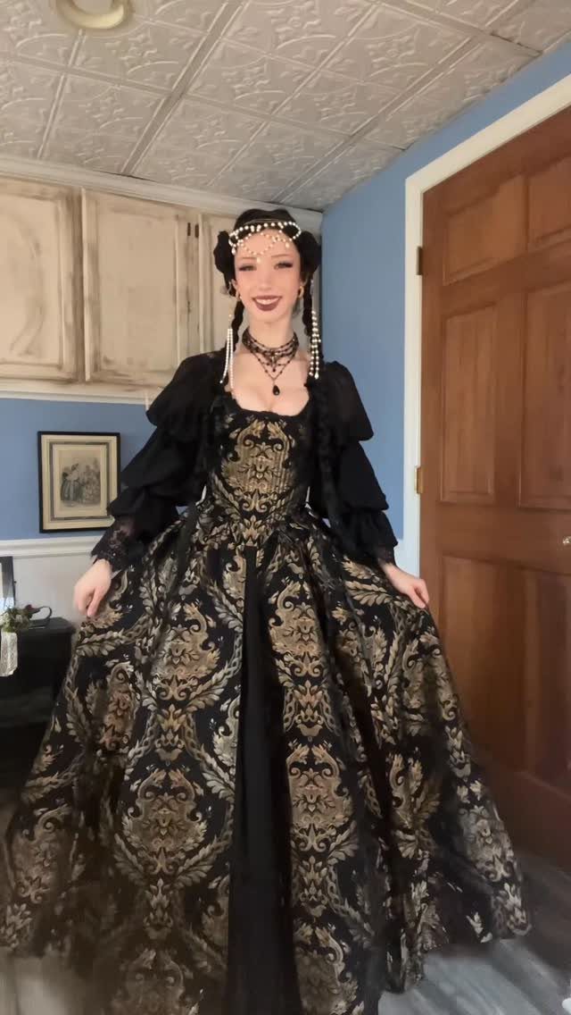 Medieval Period Dress: 12 Women's Styles and Looks 7 Woman in a black and gold brocade gown with pearl headpiece and jewelry.