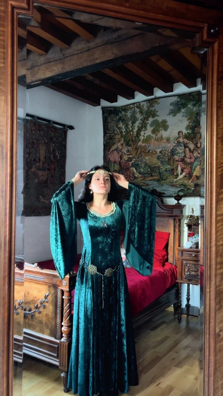 Medieval Period Dress: 12 Women's Styles and Looks 6 Woman in a green velvet medieval gown standing in a rustic bedroom