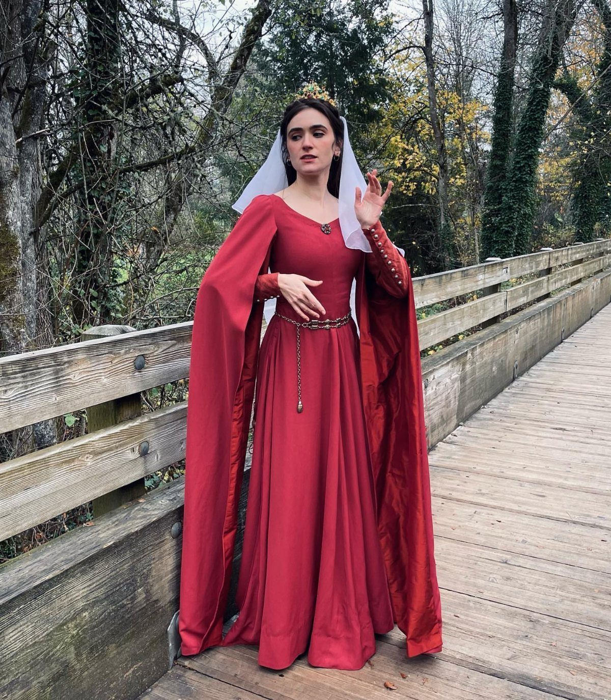 Medieval Period Dress: 12 Women's Styles and Looks 4 Woman in a long red medieval gown and white veil on a wooden bridge