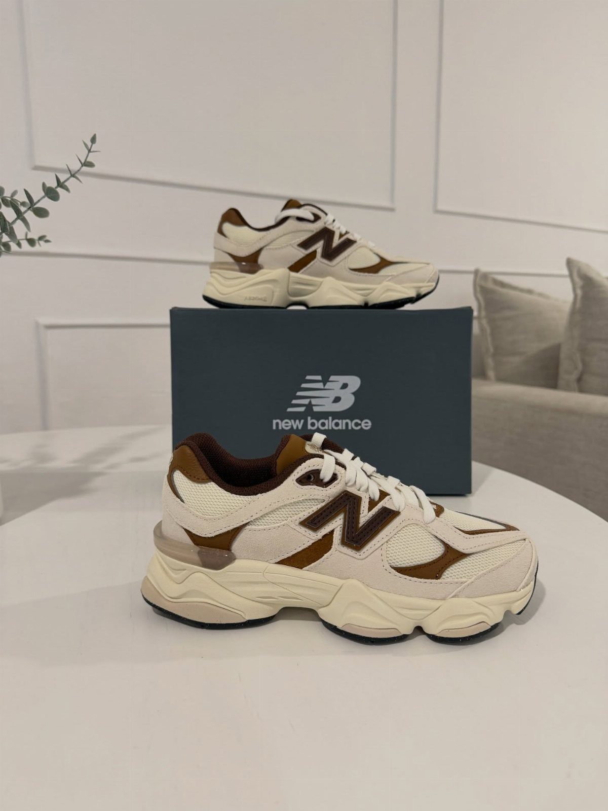 New Balance 9060 sneakers in cream and brown on a white table
