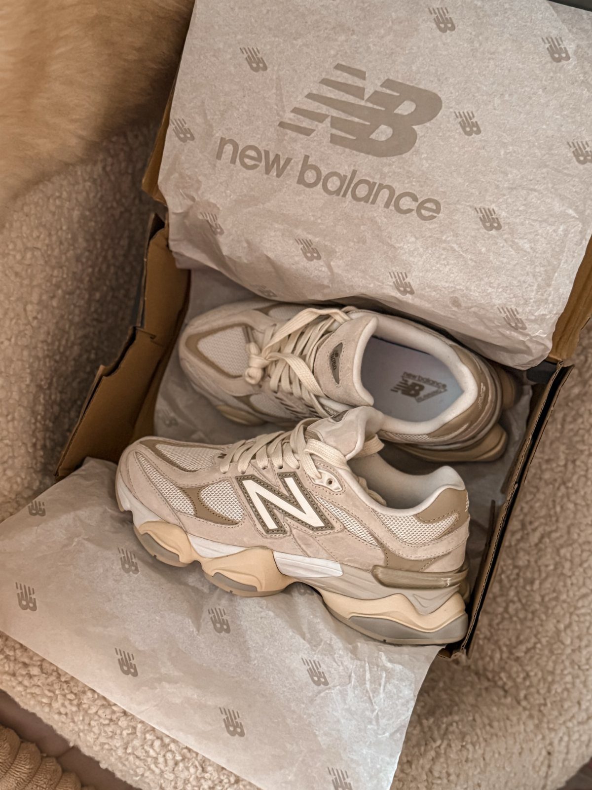 Beige New Balance 9060 sneakers in a shoebox with branded tissue paper.