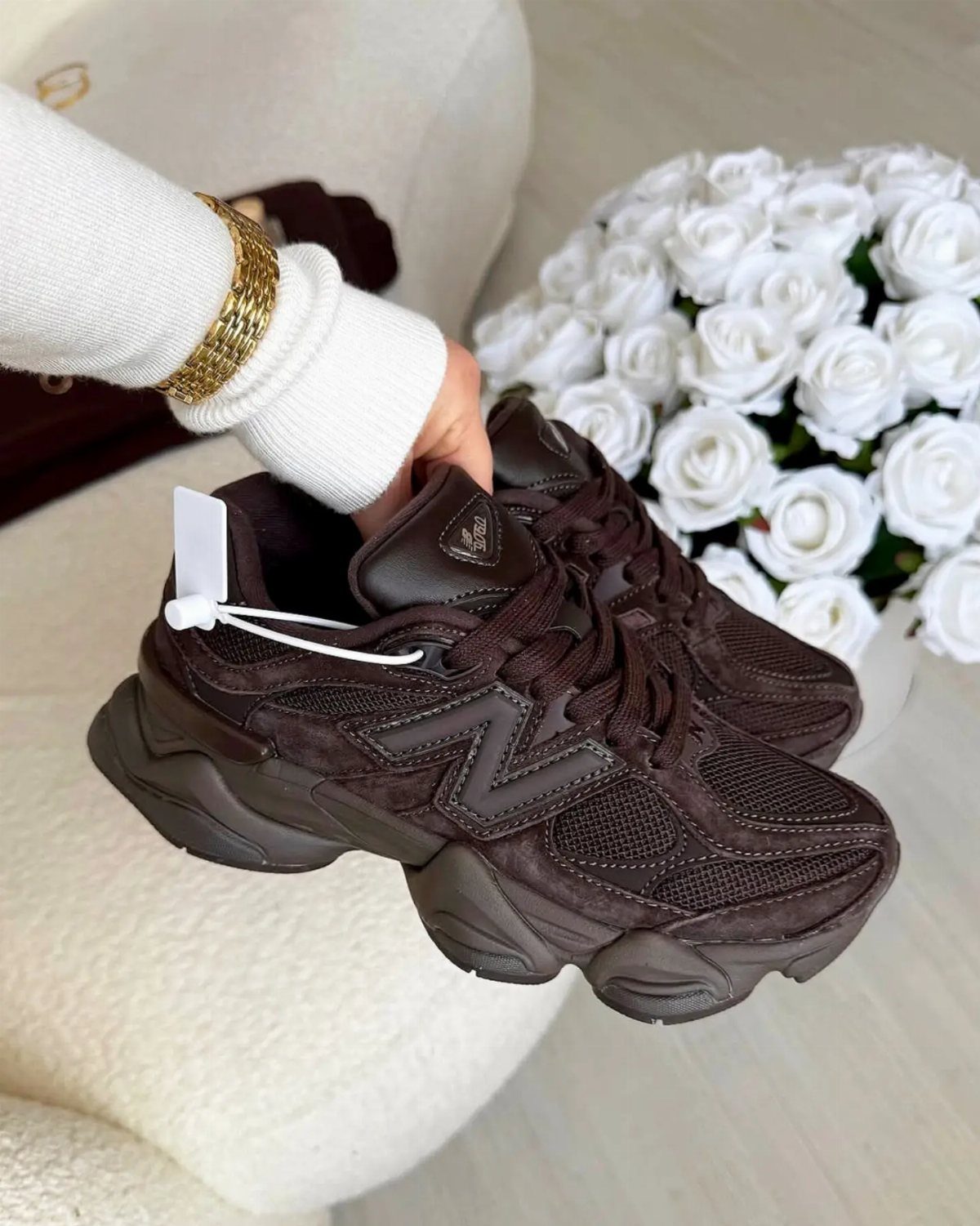 New Balance 9060 Marron Sneakers: 5 Ideas to Wear 1 Burgundy New Balance 9060 sneakers held by a hand near white roses.