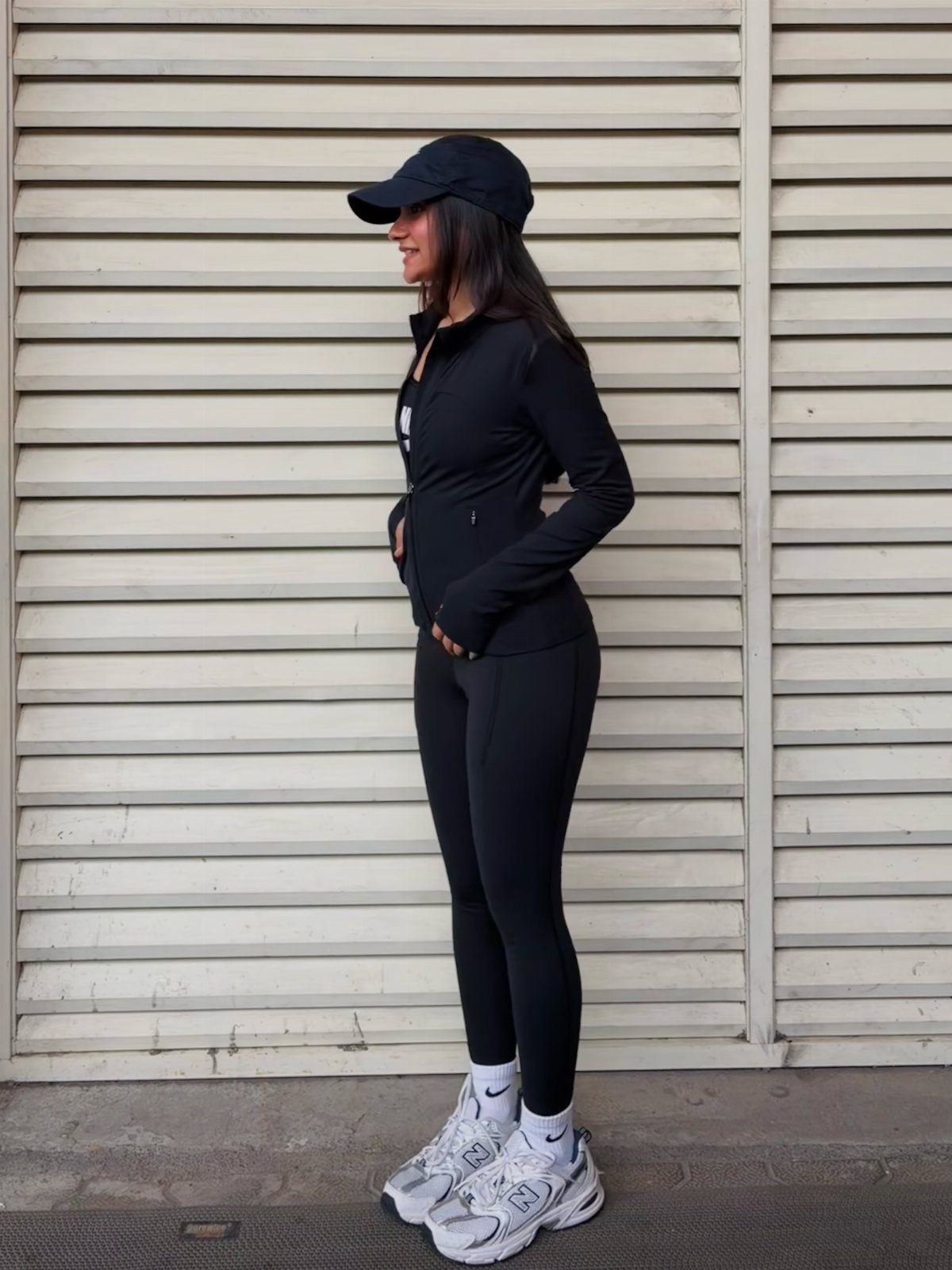 New Balance 9060 Sea Salt Moonbeam: 5 Outfit Ideas 5 Woman in black athletic wear and white chunky sneakers against a white wall