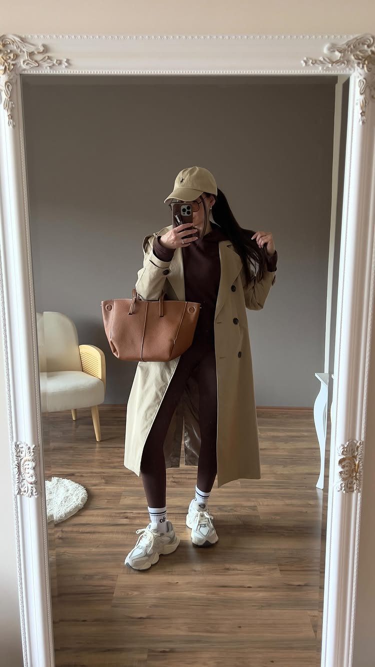 New Balance 9060 Sea Salt Moonbeam: 5 Outfit Ideas 2 Person in a beige trench coat and brown leggings wearing chunky white sneakers.