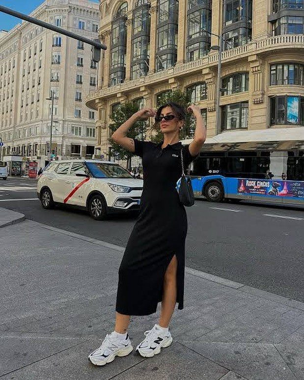 Woman in black midi dress and white chunky sneakers posing on city street