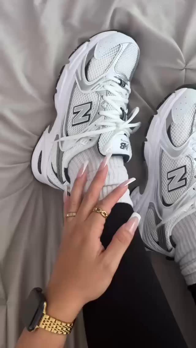 White New Balance 530 sneakers worn with black leggings and white socks.