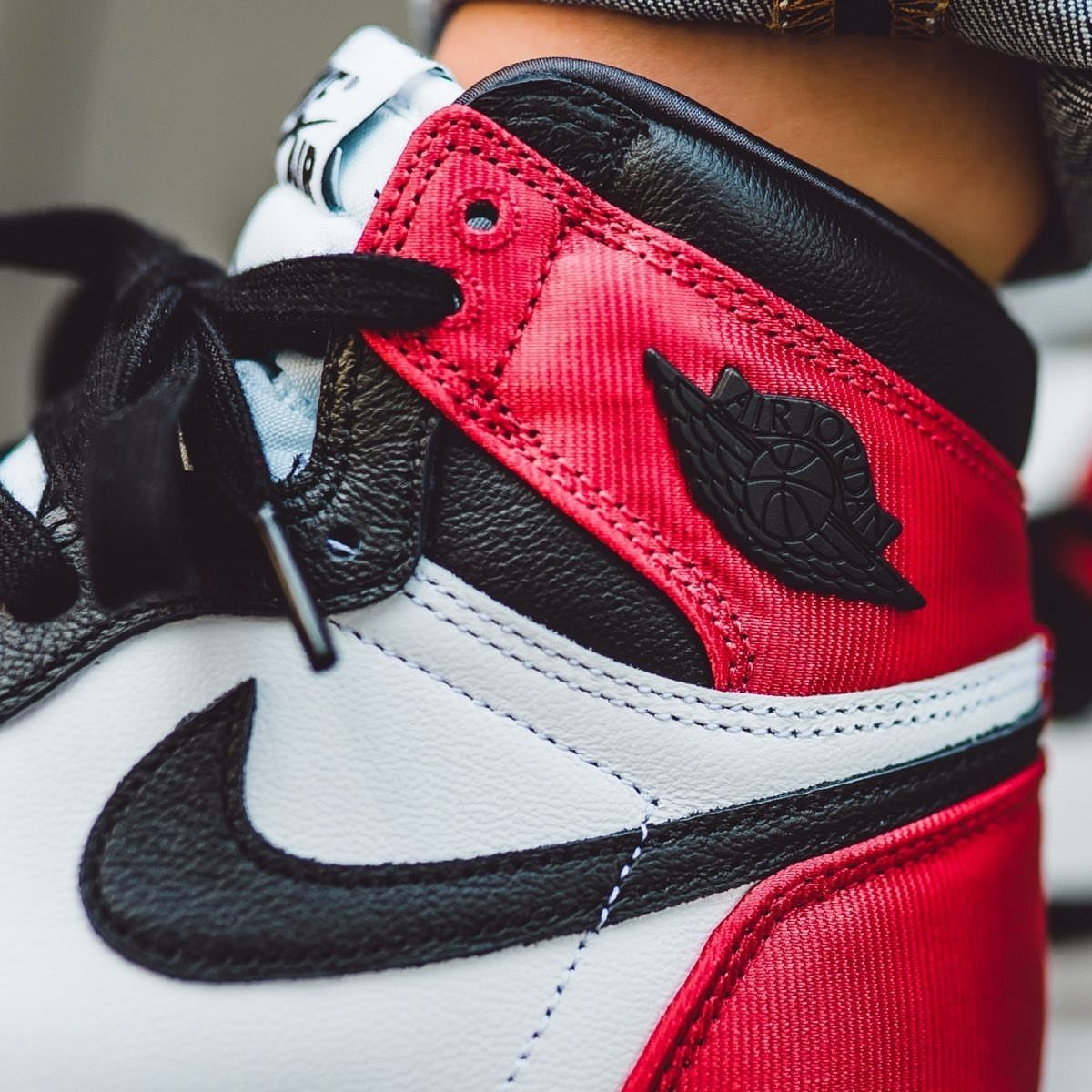 Nike Jordan Sneakers for Women: 12 Pairs to Know 4 Air Jordan 1 sneaker with red satin accents, white leather, and black swoosh.