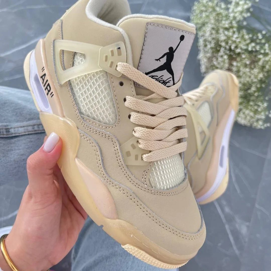 Nike Jordan Sneakers for Women: 12 Pairs to Know 1 Cream Air Jordan 4 Off White Sail sneakers held by a hand.