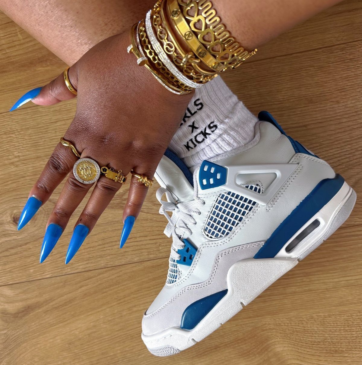 Nike Jordan Sneakers for Women: 12 Pairs to Know 9 White and blue Air Jordan 4 sneakers worn by a person with blue nails.