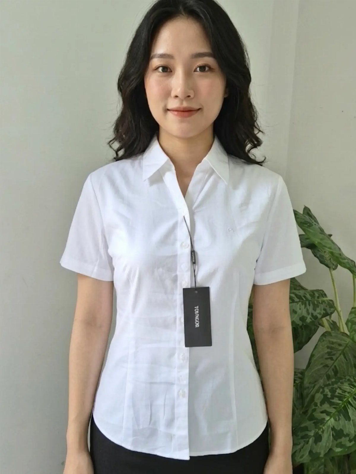 Woman wearing a white short-sleeve collared office blouse and black skirt.