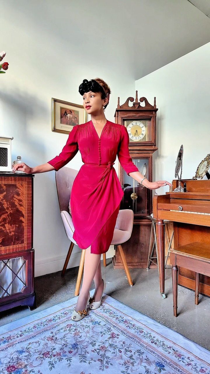 Old Hollywood Style Dresses: 9 Ideas in Satin, Lace and Black 5 Woman in a fitted red draped dress posing in a vintage room.