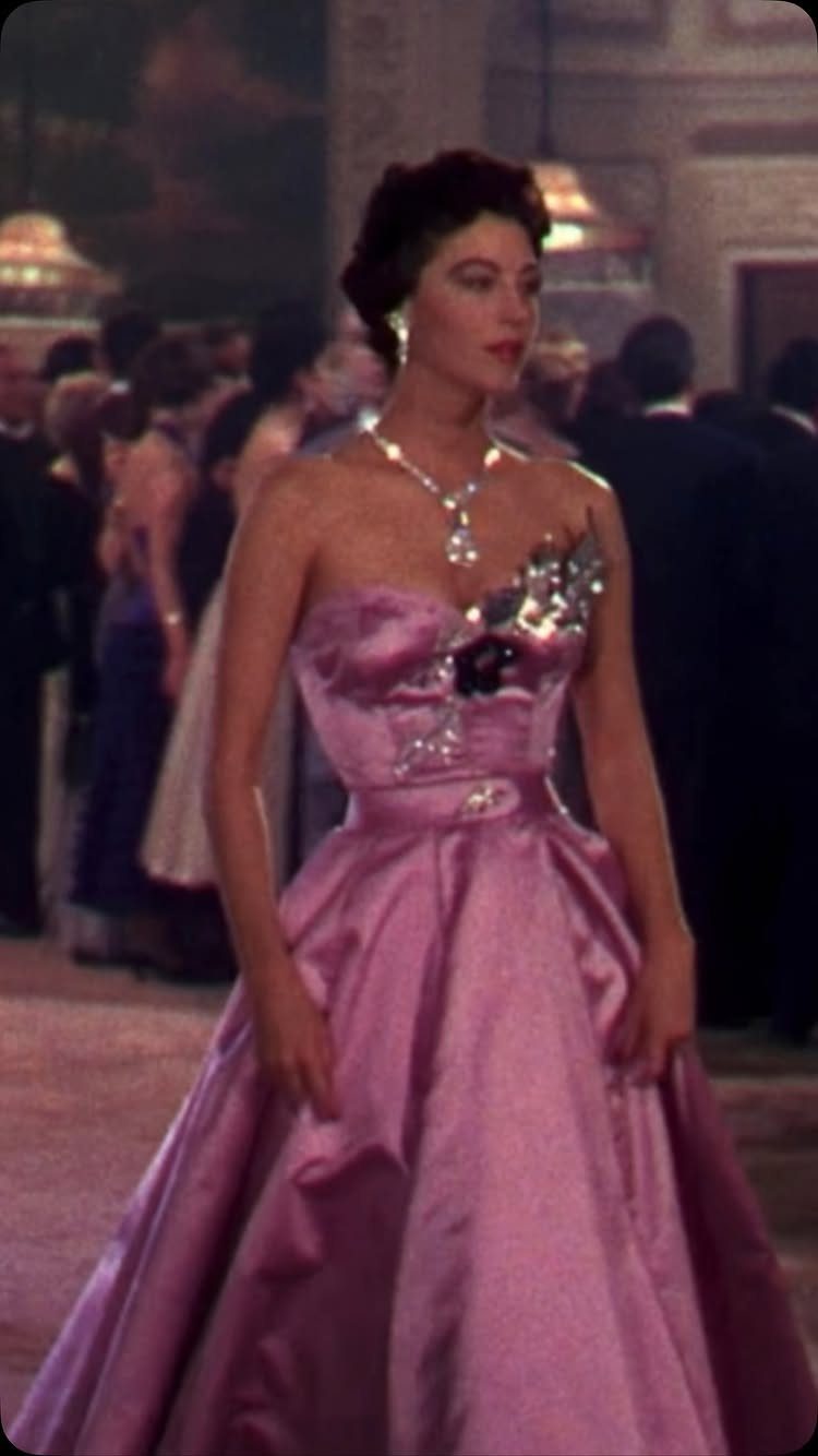 Old Hollywood Style Dresses: 9 Ideas in Satin, Lace and Black 1 Woman in a shimmering pink strapless satin ballgown and diamond necklace in a ballroom