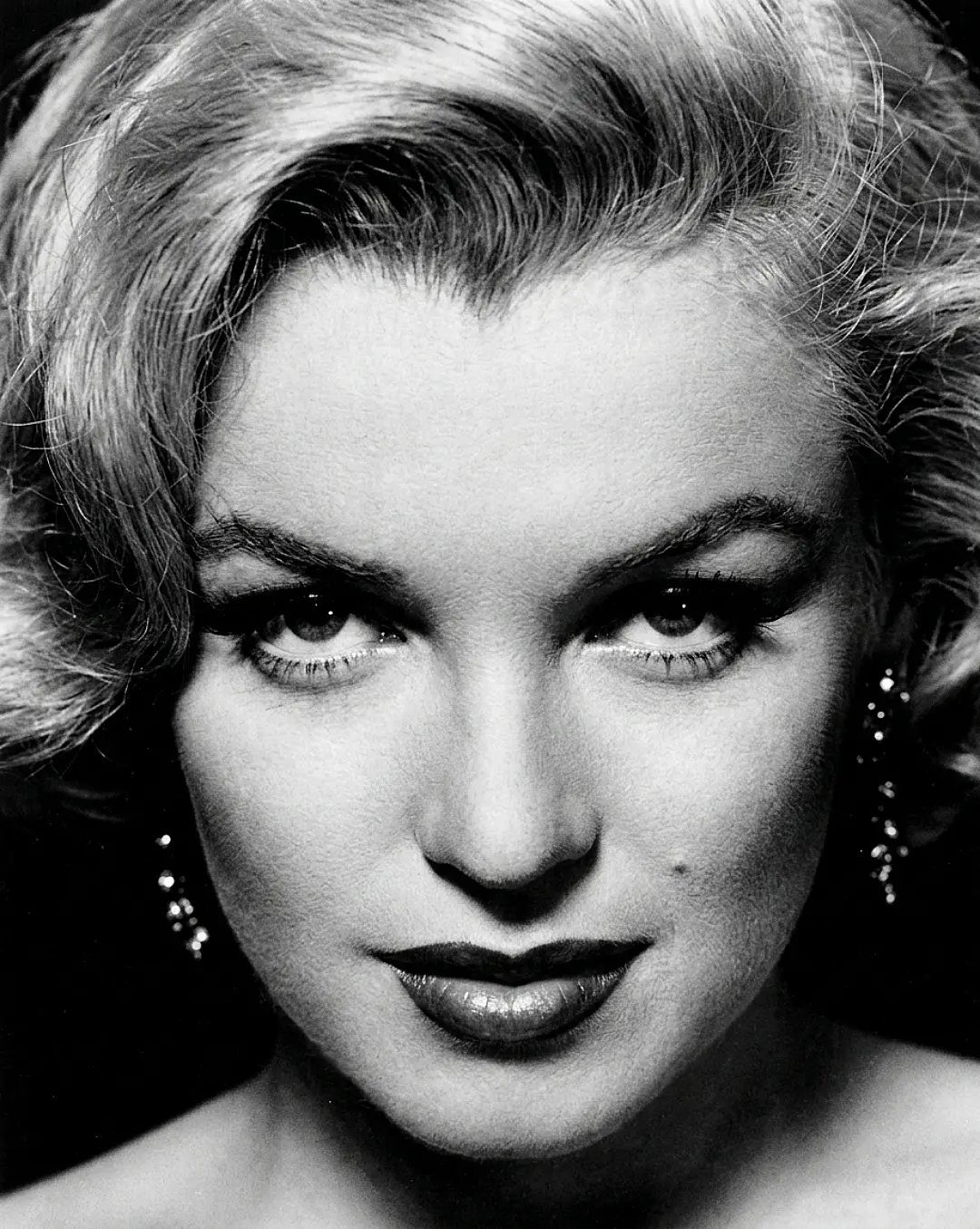 Woman with blonde wavy hair and dramatic makeup in black and white portrait