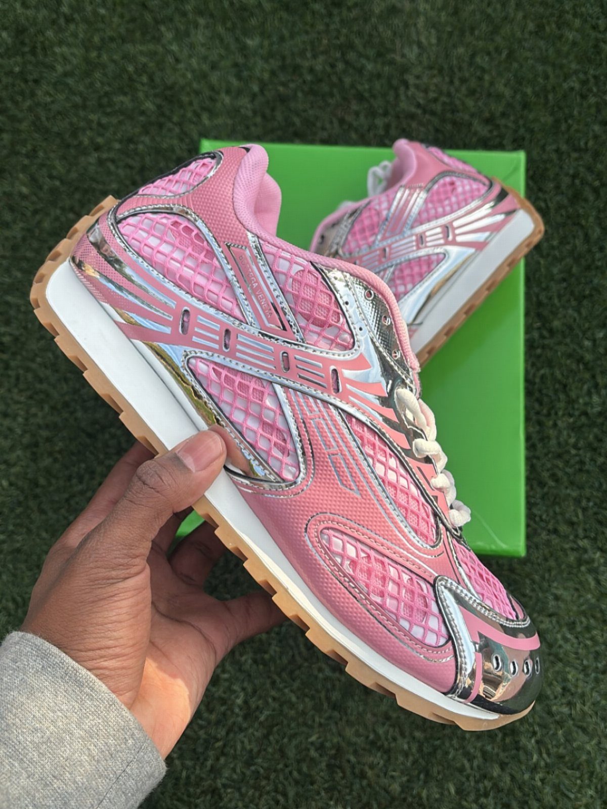 Pink and White Designer Sneakers: 5 Pairs for Women 4 Pink and silver metallic Bottega Veneta Orbit sneakers held over a green box.