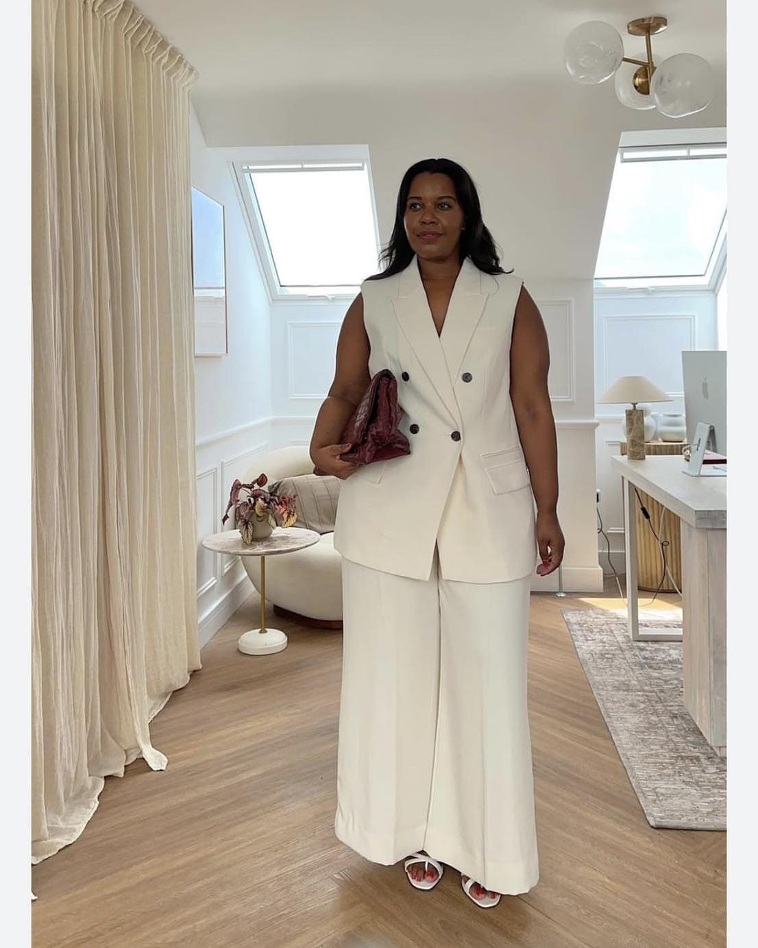 13 Plus Size Brunch Outfit Ideas for Every Style 4 Plus-size woman wearing a sleeveless white blazer and wide-leg pants with red clutch.
