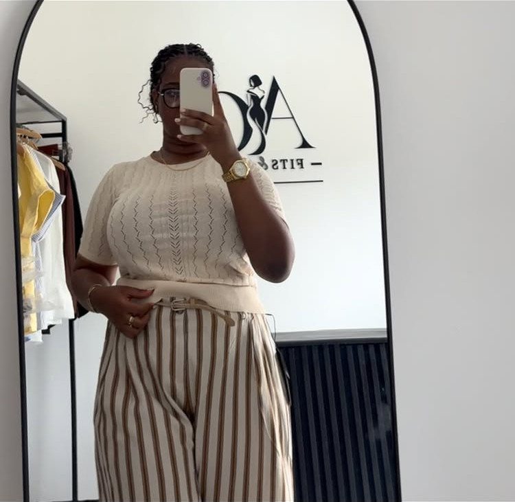 13 Plus Size Brunch Outfit Ideas for Every Style 2 Plus-size woman in cream knit top and striped wide-leg trousers taking mirror selfie