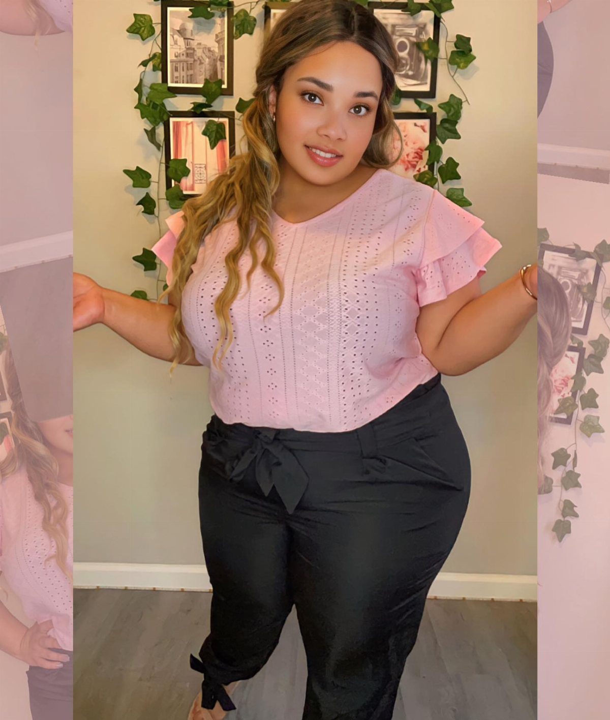 13 Plus Size Brunch Outfit Ideas for Every Style 13 Plus-size woman wearing a pink ruffled eyelet blouse and black tie-waist trousers.