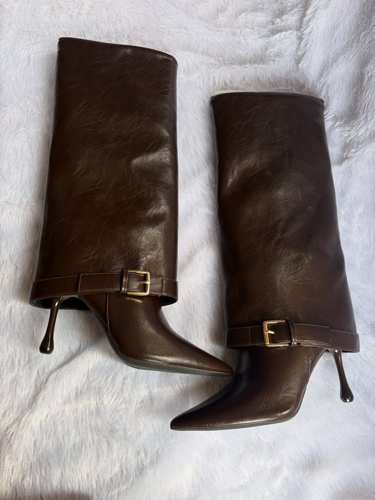 Dark brown leather boots with pointed toes, stiletto heels, and gold buckle straps.