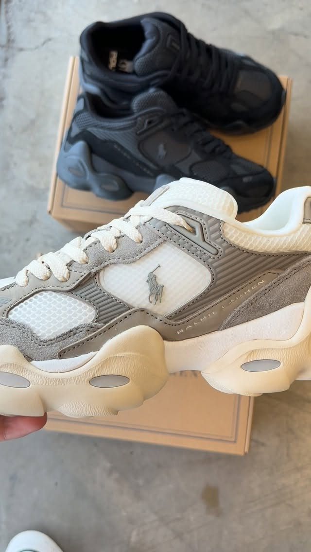 Beige and white chunky sneakers held in front of black chunky sneakers.