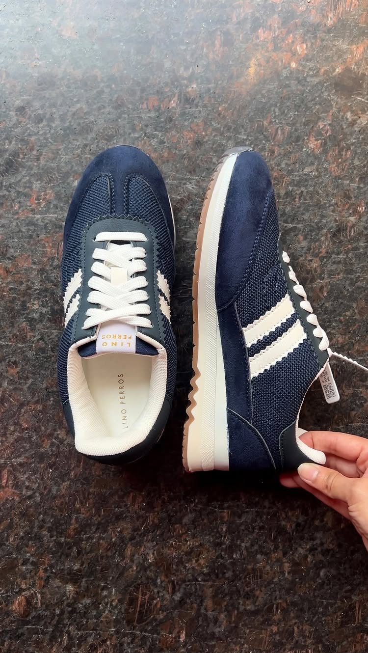 Navy blue suede and mesh sneakers with white stripes on dark brown surface