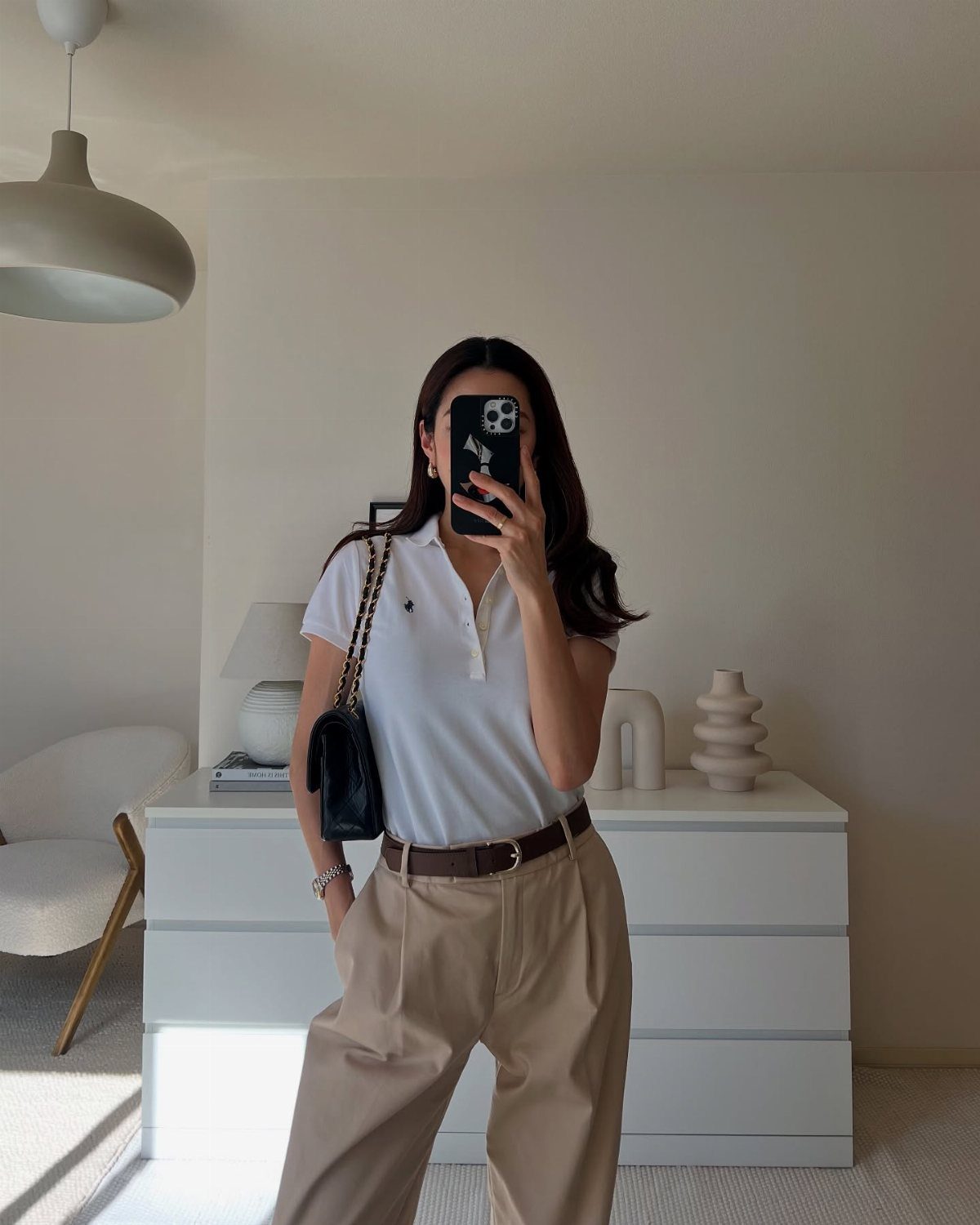 Ralph Lauren Polo Fits for Every Day: 10 Outfit Ideas 1 Woman wearing a white short-sleeve polo shirt and beige high-waisted trousers.