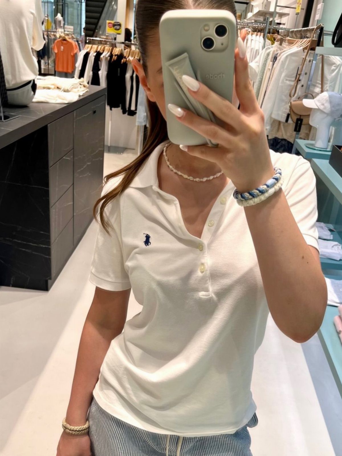 Ralph Lauren Polo Fits for Every Day: 10 Outfit Ideas 3 Woman in white polo shirt and pinstripe trousers taking a mirror selfie.