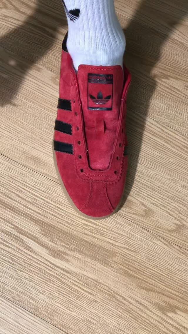 8 Red Trendy Shoes for Sneaker and Flat Lovers 1 Red suede Adidas Gazelle sneaker with black stripes on a wooden floor