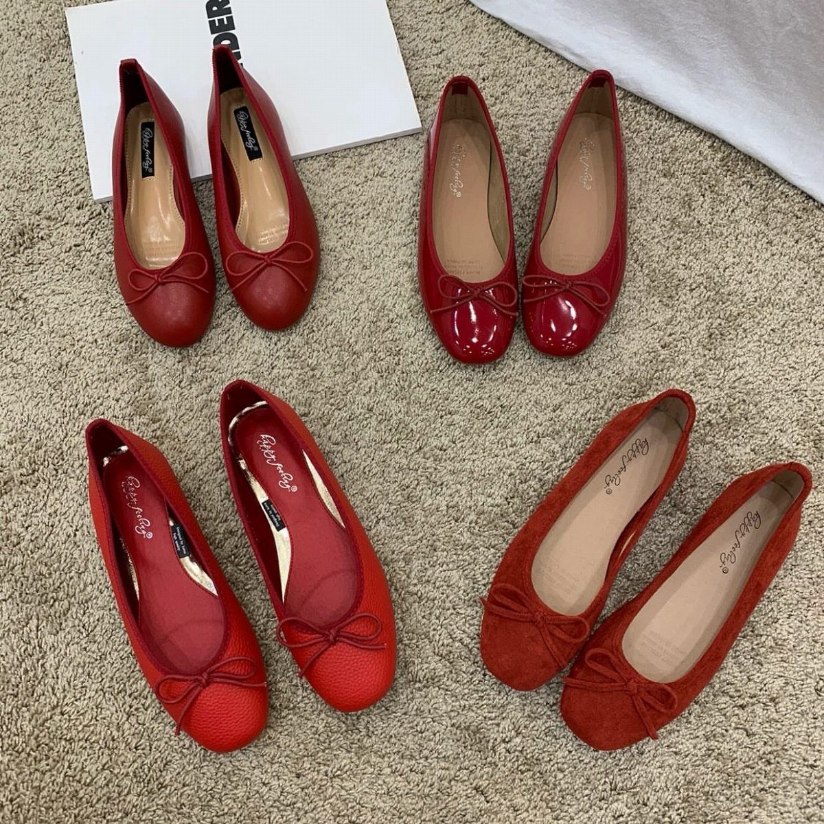 8 Red Trendy Shoes for Sneaker and Flat Lovers 5 Four pairs of red ballet flats in various textures arranged on a beige carpet.