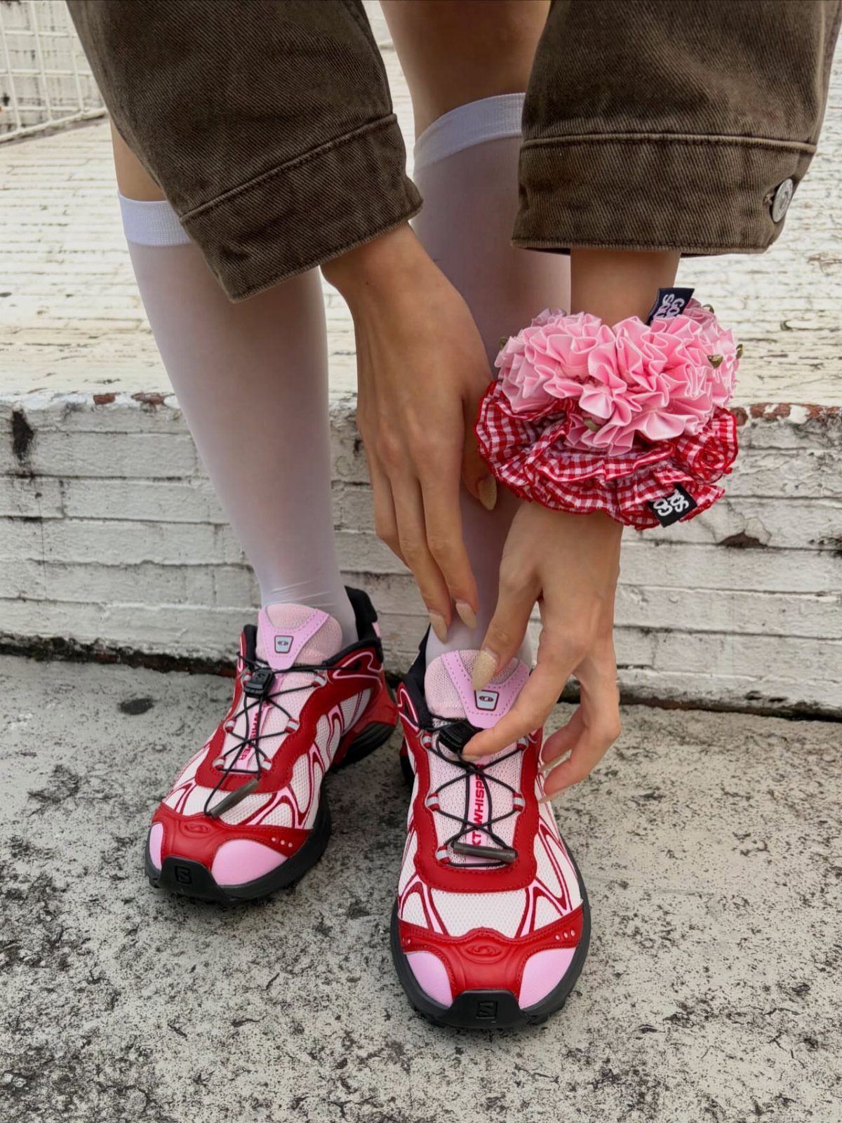 8 Red Trendy Shoes for Sneaker and Flat Lovers 4 Chunky red and pink Salomon sneakers worn with white socks and brown trousers.