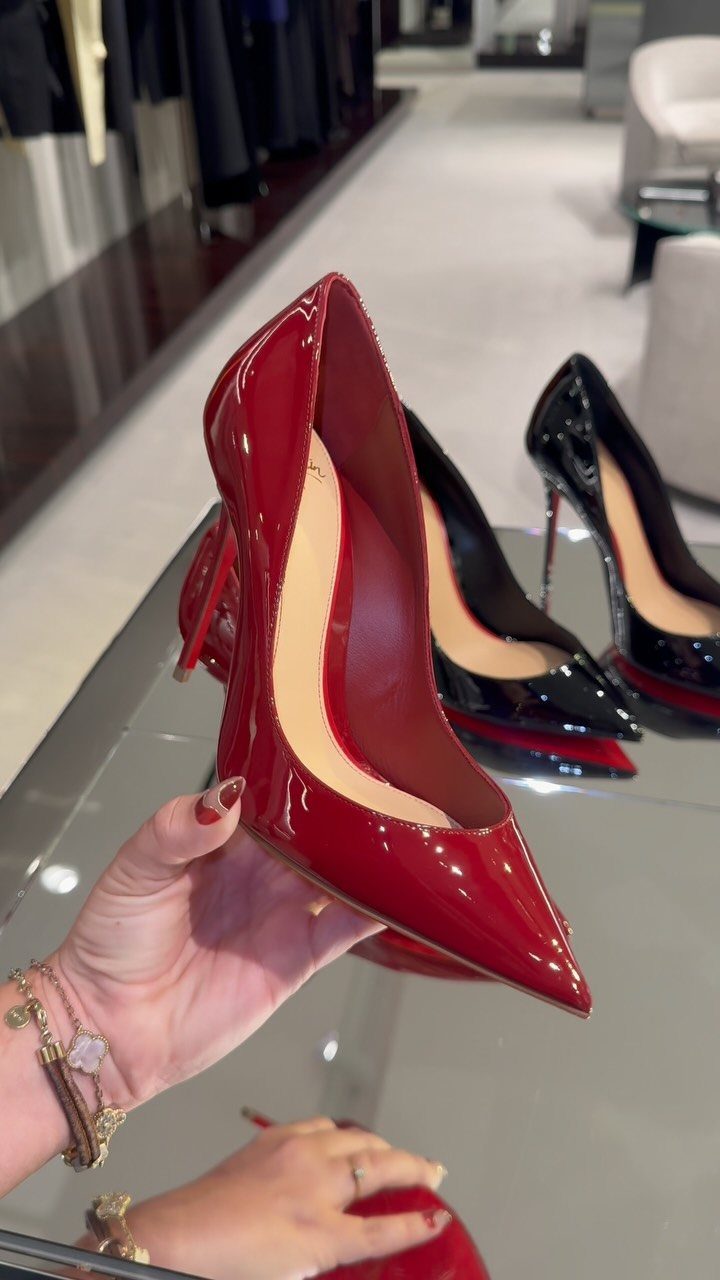 8 Red Trendy Shoes for Sneaker and Flat Lovers 6 Crimson red pointed-toe pump heel held by a hand in a luxury store.