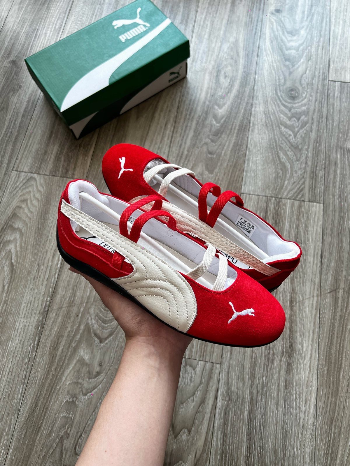 8 Red Trendy Shoes for Sneaker and Flat Lovers 2 Red and white Puma ballet-style sneakers held over a grey wooden floor.