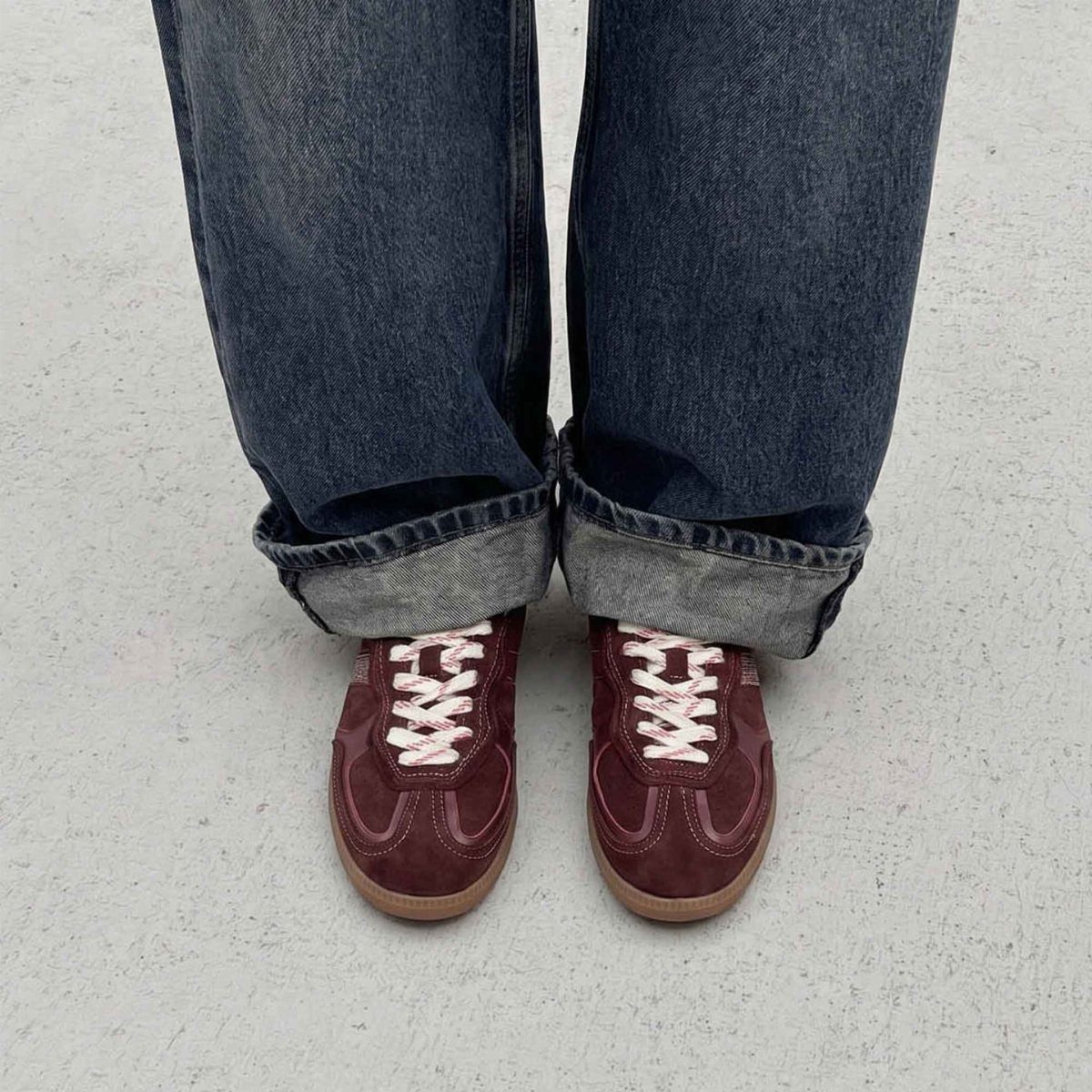 8 Red Trendy Shoes for Sneaker and Flat Lovers 3 Burgundy suede sneakers with white laces worn with cuffed blue jeans.