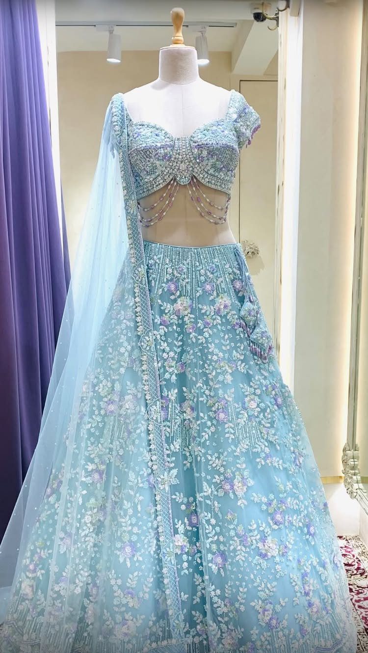 Light blue embroidered lehenga choli on a mannequin with soft pastel floral details.