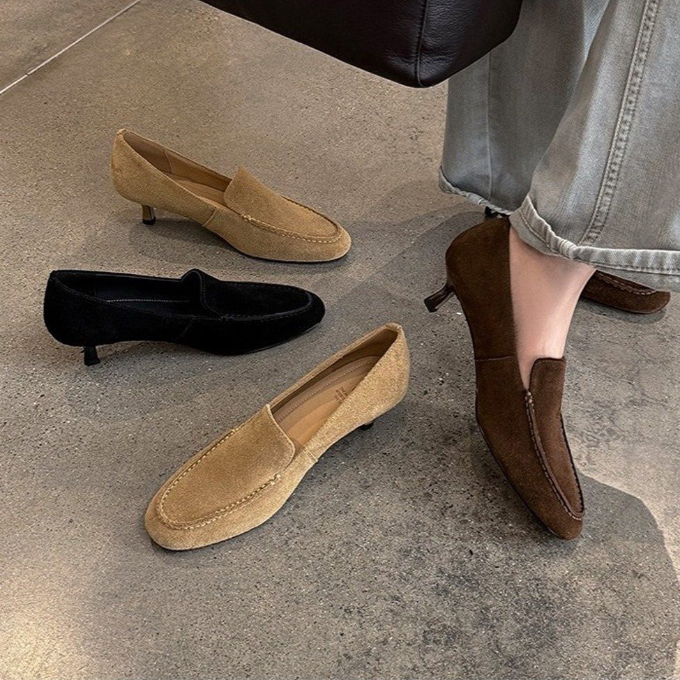 Round toe kitten heel loafers in tan and black suede on concrete floor.