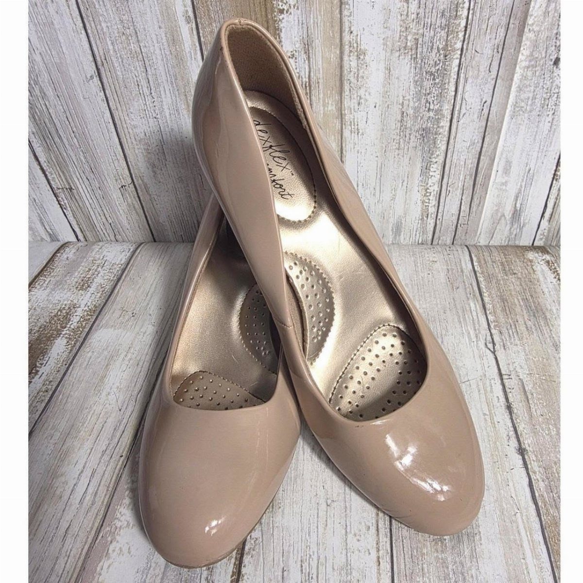 Nude patent leather round toe kitten heels on a weathered white wood background