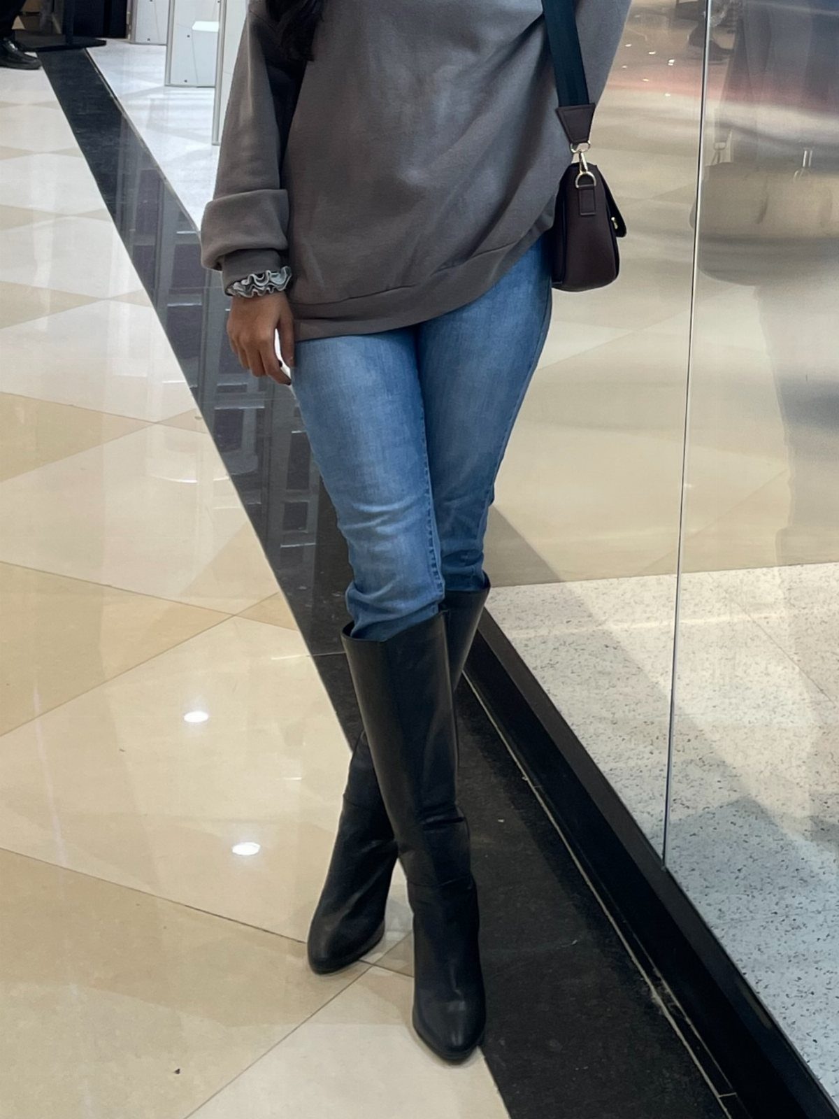 Shin High Boots: 5 Ideas from Suede to Wide Calf Styles 5 Black leather shin-high boots worn with blue jeans and a grey sweatshirt.
